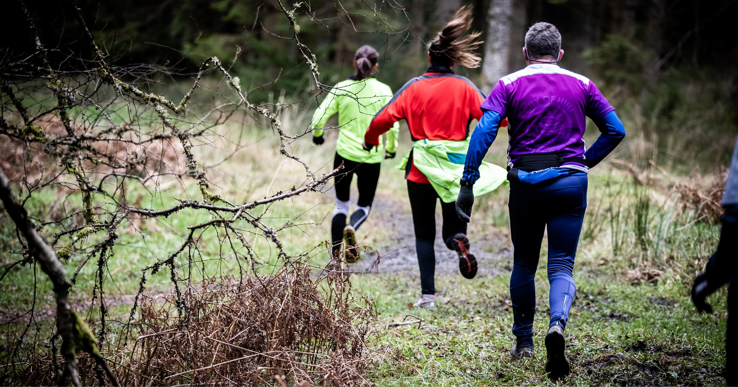 group of people running through a forest